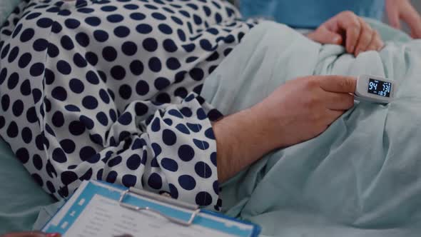 Closeup of Sick Man Patient Resting in Bed with Medical Oximeter on Finger alt