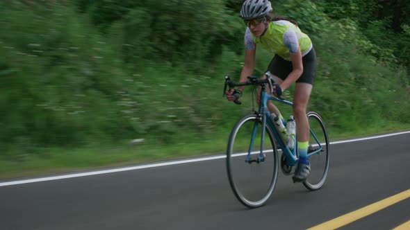 Tracking shot of a female cyclist on country road.  Fully released for commercial use.