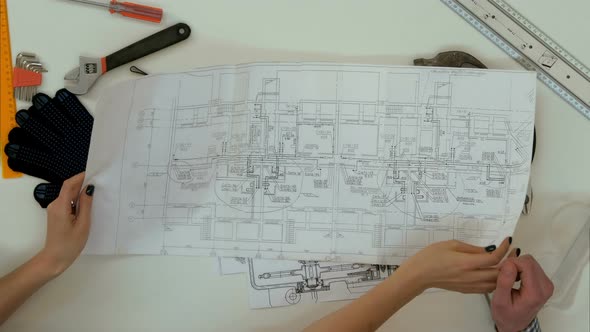 Architects Working on Blueprints with Divider Compass