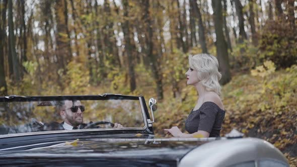 Lady Looking on Man Cabriolet Under Falling Autumn Leaves alt