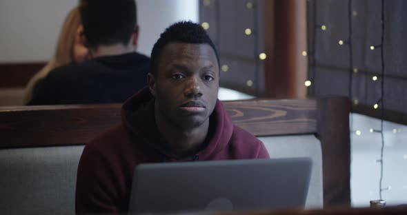 Bored Young Man with Laptop in Cafe alt