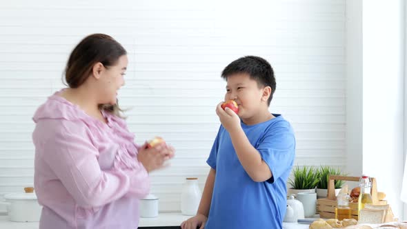 Fat woman and boy eating an apple in the kitchen, organic nutrition, vitamin C, diet concept
