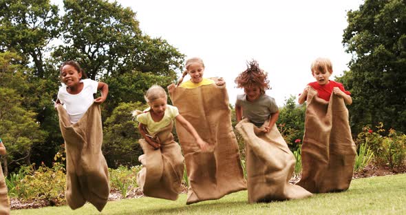 Kids having a sack race in park alt