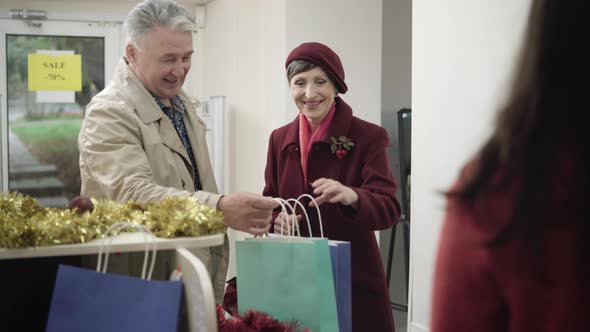 Portrait of Happy Senior Caucasian Couple Buying Presents on Christmas Sales. Smiling Man and Woman alt