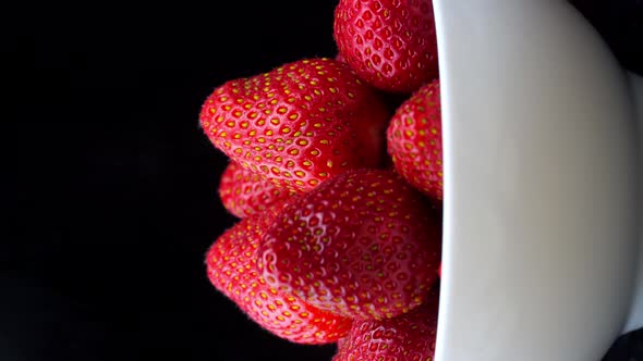 Strawberries without tails lie in white bowl or plate. It rotates alt