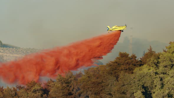 Fire fighter plane drops fire retardant on a forest fire in the hills alt