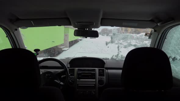 Man cleaning car windshield from snow and ice alt