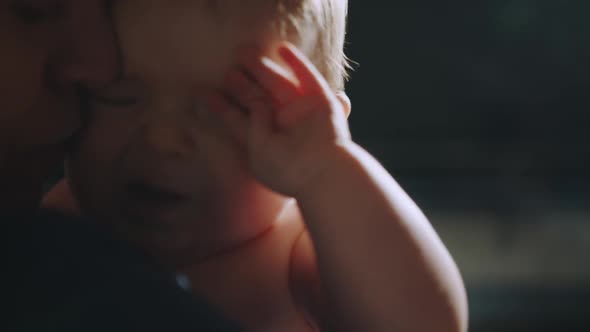 Mother Holding Cute Newborn Baby in Cozy Dark Kids Bedroom in the Evening alt