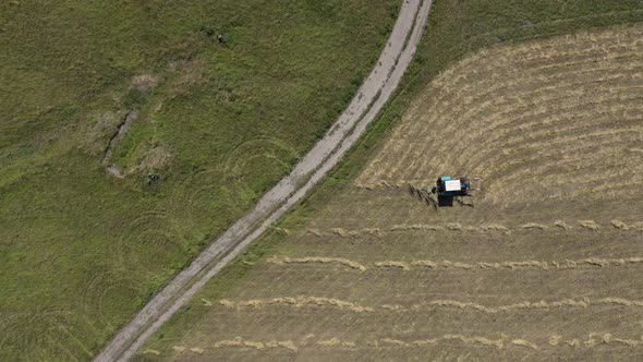 Bird Eye View of Tiny Tractor Collecting Dry Hay in the Field