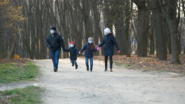 Family: father, mother, son and daughter walk in the Park in medical masks in the spring.
