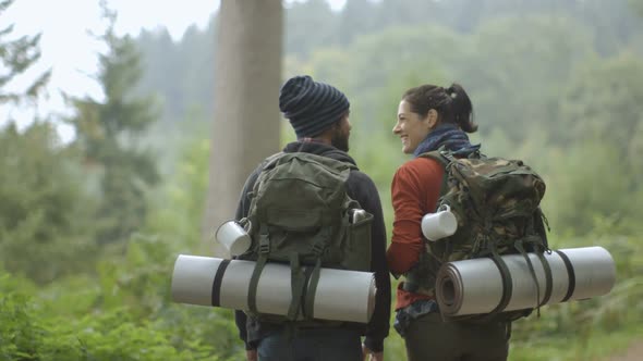 Couple carrying rucksacks and walking through trail