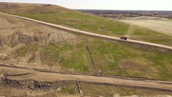 Industrial dump truck transporting soil up to landfill, aerial drone view alt