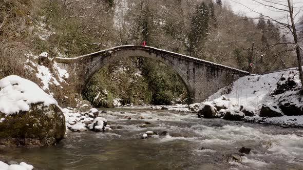 Man walking on historic stone bridge from aerial with drone
