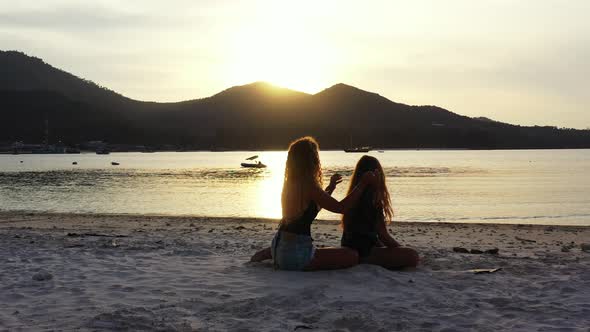 Women playing with hair on calm exotic beach at romantic moments of sunset with sun setting down mou alt