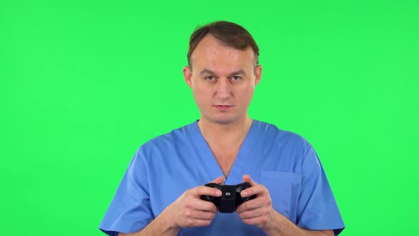 Medical Man Playing a Video Game Using Wireless Controller and Rejoicing in Victory. Green Screen alt