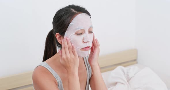 Woman apply paper mask on bed alt