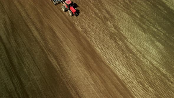 Spring agricultural land. Tractor with a cultivator on a spring field. Aerial photography. alt