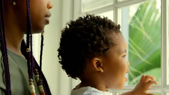 Close-up of young black mother playing with his son on window sill in a comfortable home 4k alt