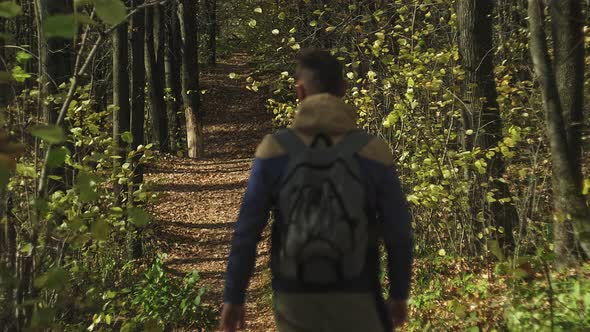 A Mature Man Tourist Traveler with a Backpack Walks in the Autumn Forest Near the River