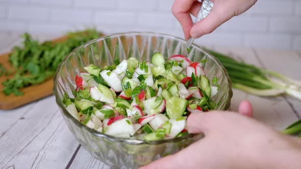 Hands Chef Stirring with a Spoon a Vegetable Salad with Radish Cucumber Greens alt