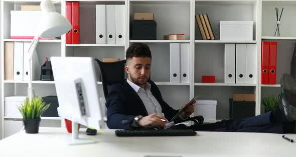 Businessman Working with Legs on Table in Office