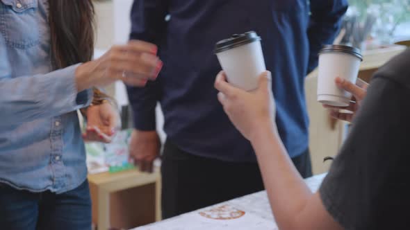Young barista serving order coffee cup to customer man and woman while takeaway. alt