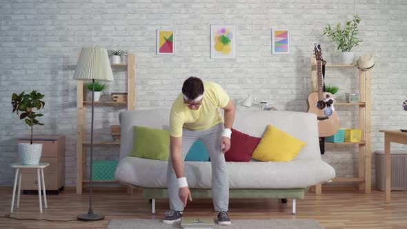 Expressive Joyful Funny Man in Sportswear Uses Floor Scales alt