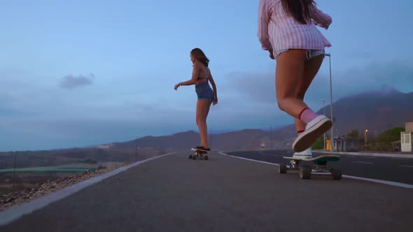 Close - Up of a Skateboard and Two Girls Who Are Riding on Boards From a Mountain on a Background of alt
