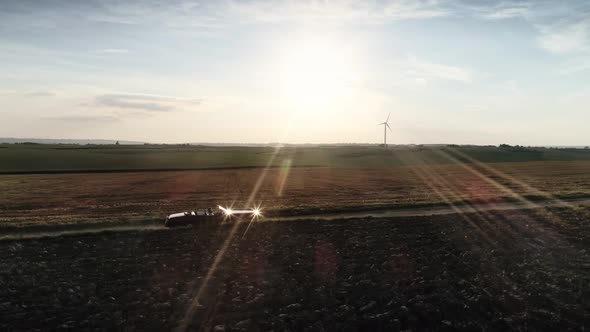 Red car drives down country road at a summer sunset. Shot with RED helium camera in 8K alt