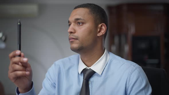 Young African American Man Doing Eye Exercises and Looking at Camera Sitting in Home Office Indoors alt