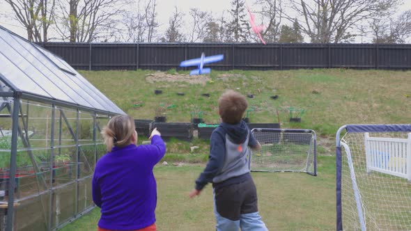 Beautiful view of grandmother and grandchild playing with  toy planes on backyard. alt