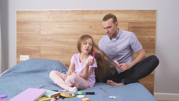 Funny Time Young Caucasian Father Doing His Daughter's Hair in Her Bedroom