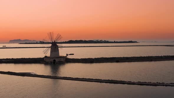 Aerial Orbit drone Shot Around a Mill in Salt Pans of Marsala in Sicily during sunset, Italy 4K