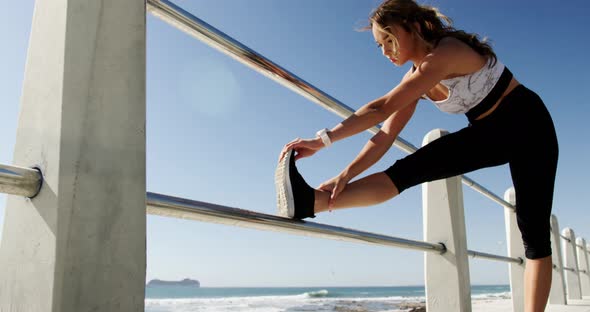 Beautiful Caucasian woman exercising on railing at beach 4k
