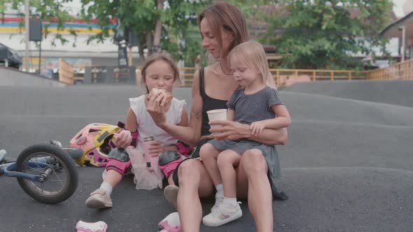 Mother and Daughters Having Bite Outdoors alt