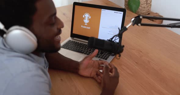 Young african man doing podcast using computer laptop at home - Technology trend concept alt