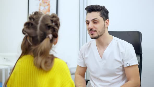 Cheerful Young Middle Eastern Doctor Talking with Girl Indoors alt
