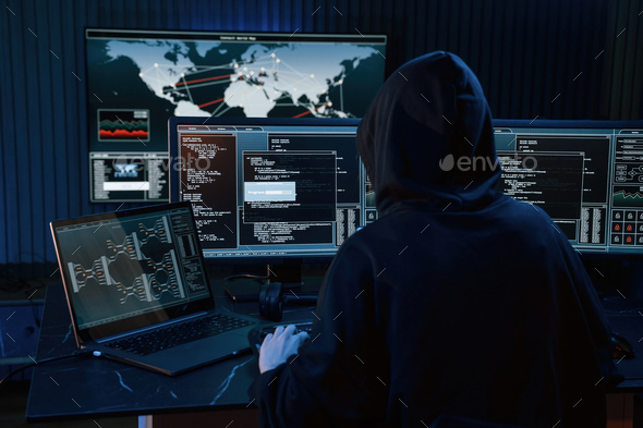 Young professional female hacker is indoors by computer with lot of information on displays