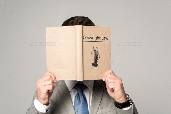 lawyer obscuring face with copyright law book isolated on grey