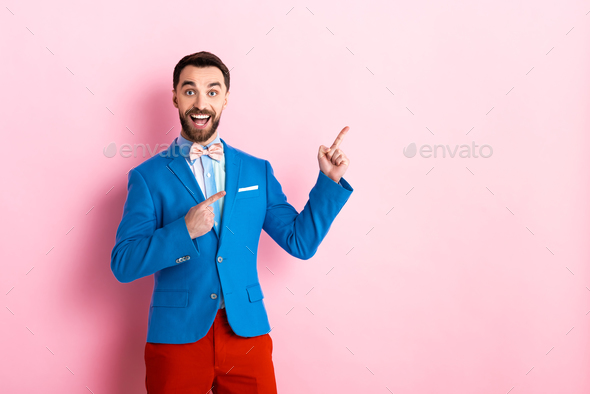 excited man in suit pointing with fingers on pink