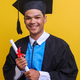 Young Asian man wearing graduation robe holds diploma certificate 