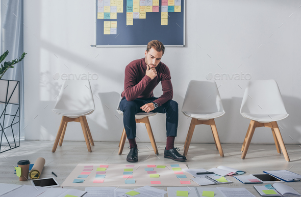 pensive businessman sitting on chair near sticky notes - Stock Photo - Images