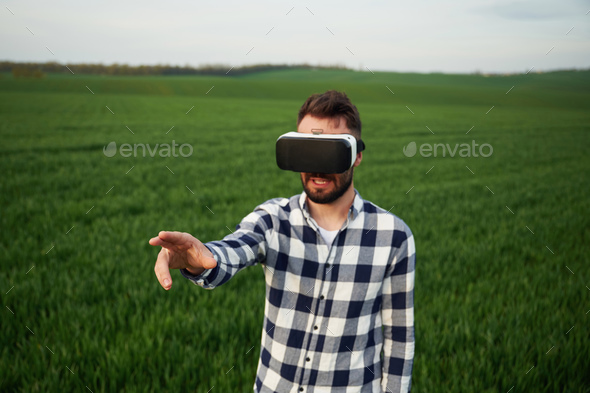 Conception of gaming. In virtual reality glasses. Handsome young man is on agricultural field - Stock Photo - Images