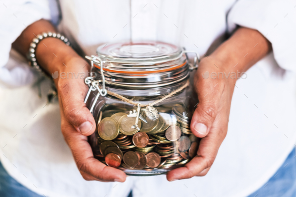 Woman hands holding a glass jar full of coins saving to travel and realize dreams lifestyle