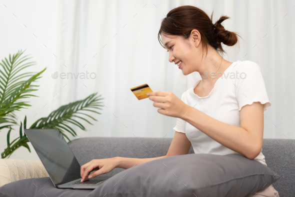 Teenage girl is holding credit card and typing credit card number for payment after shopping online
