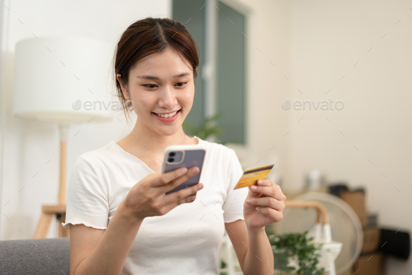 Teenage girl is holding credit card and typing credit card number for payment after shopping online