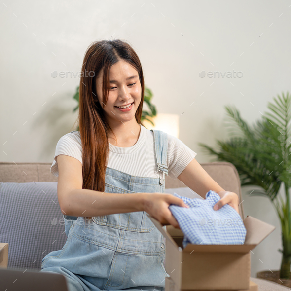 entrepreneur is packing clothes into cardboard boxes for home delivery to customers while sitting