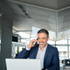 Happy older business man talking on cell phone using laptop in office. - PhotoDune Item for Sale