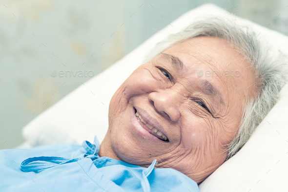 Asian elderly woman patient smile bright face with strong health while lying on bed in hospital. - Stock Photo - Images