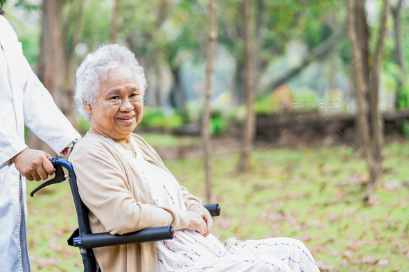 Doctor help and care Asian elderly woman patient sitting on wheelchair at park in nursing hospital. - Stock Photo - Images